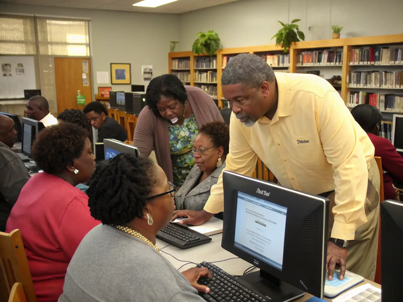 A diverse group of adults attending a workshop on digital literacy at the library, with laptops and tablets in front of them.